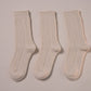 Three pairs of white socks on a beige background
